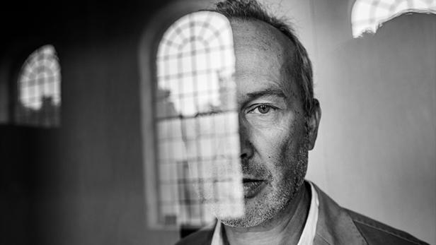 Ein Mann steht vor einem Fenster mit Bleiglas in Schwarzweiß.