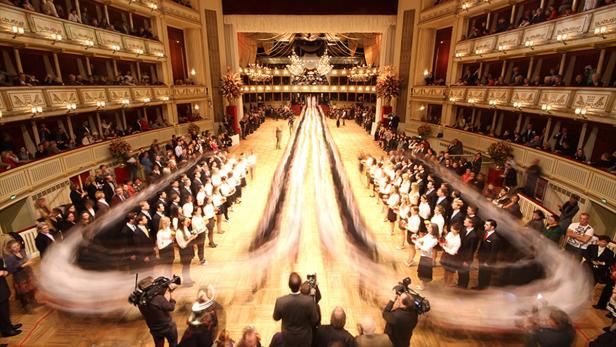 Blick in den Ballsaal der Wiener Staatsoper mit Debütantenpaaren und Zuschauern auf den Rängen.