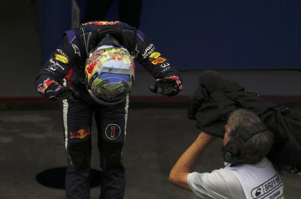 Ein Formel-1-Fahrer mit gesenktem Kopf hält seinen Helm in der Hand.