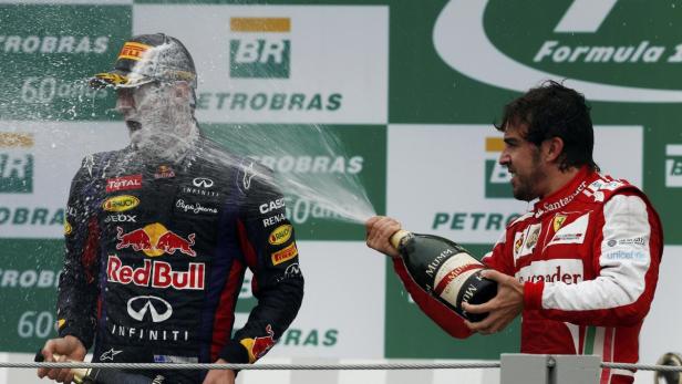 Sebastian Vettel wird auf dem Formel-1-Podium mit Champagner von Fernando Alonso übergossen.