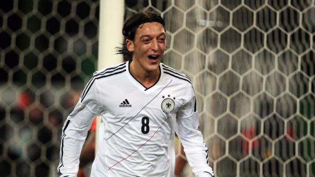 Mesut Özil im Trikot der deutschen Nationalmannschaft jubelt vor einem Tornetz.
