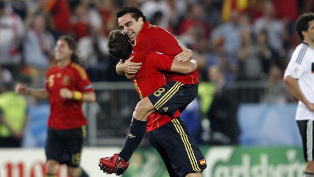 Die spanischen Fußballspieler Xavi und Iniesta umarmen sich während eines Spiels.