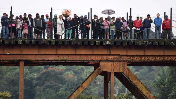 Eine Gruppe von Menschen steht auf einer alten Eisenbahnbrücke.