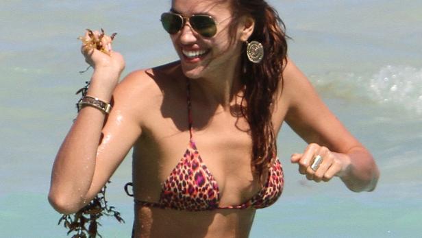 Jessica Alba im Bikini steht im Wasser und hält Seetang in der Hand.