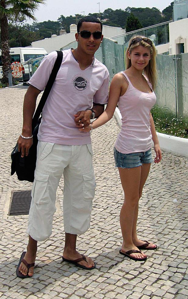 Ein junges Paar geht Händchen haltend auf einem gepflasterten Weg entlang.