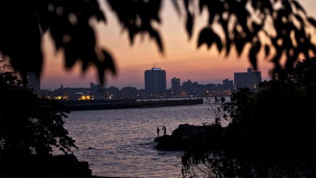 Silhouette von zwei Personen am Ufer mit Blick auf die Skyline von Havanna bei Sonnenuntergang.