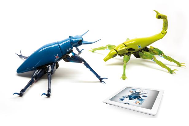 Zwei Roboterinsekten, eine blau, die andere gelb, stehen neben einem Tablet.