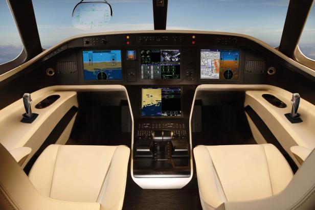 Das Cockpit eines Embraer-Jets mit beigen Ledersitzen und modernen Bildschirmen.