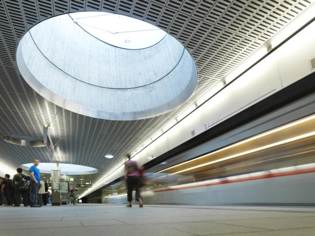 Ein Zug fährt in einen U-Bahnhof mit Oberlichtern ein.