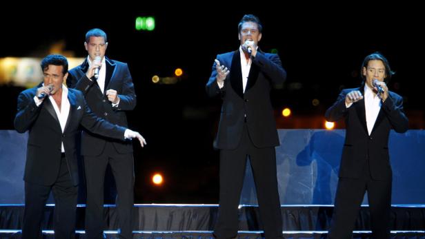 Die Gruppe Il Divo tritt in Anzügen auf einer Bühne auf.