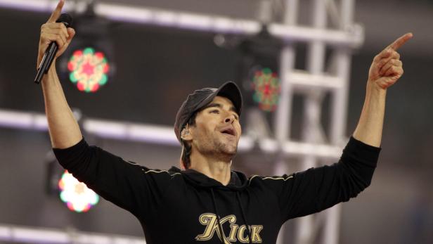 Enrique Iglesias hält ein Mikrofon in der Hand und zeigt mit dem Finger nach oben.