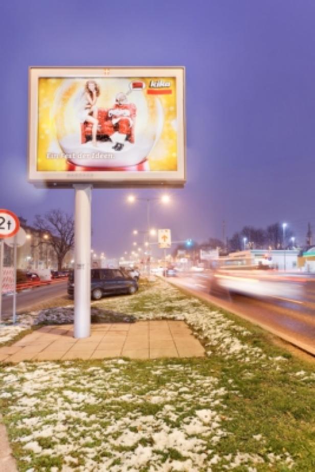 Eine Kika-Werbetafel mit einer Schneekugel, in der ein Weihnachtsmann und eine Frau sitzen.