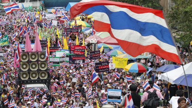 Eine große Menschenmenge demonstriert mit thailändischen Flaggen und Schildern.