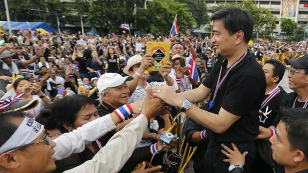 Abhisit Vejjajiva gibt Anhängern die Hand inmitten einer Menschenmenge.