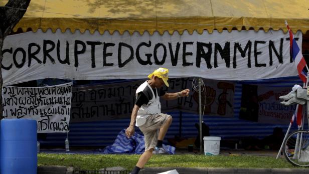 Ein Mann demonstriert vor einem Zelt mit der Aufschrift „Corrupted Government“.