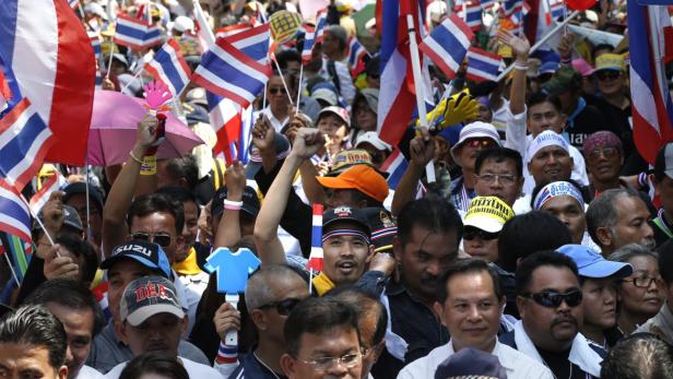 Eine Menschenmenge schwenkt thailändische Flaggen bei einer Kundgebung.