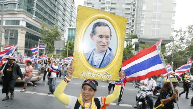 Eine Frau hält ein Porträt des thailändischen Königs bei einer Demonstration in die Höhe.