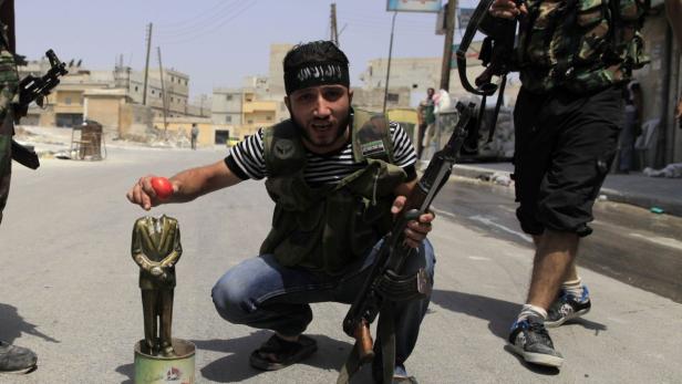 Ein Kämpfer der Freien Syrischen Armee mit einer geköpften Assad-Figur.
