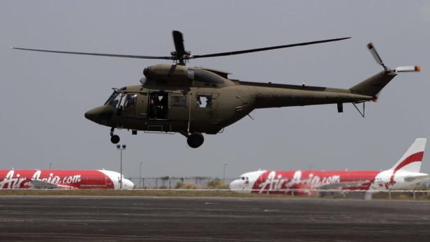 Ein Hubschrauber der philippinischen Luftwaffe schwebt über dem Rollfeld mit Air-Asia-Flugzeugen.