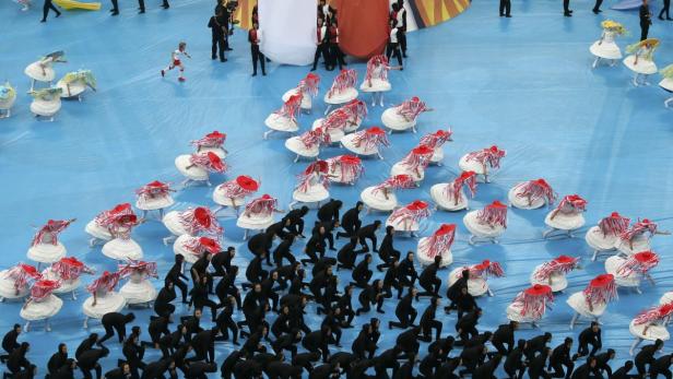 Eine Gruppe von Tänzern in Kostümen tritt auf einer blauen Bühne auf.