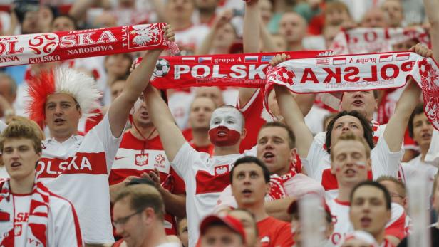 Eine Menschenmenge jubelt mit polnischen Flaggen und rot-weißen Accessoires.