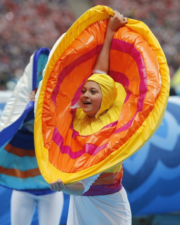 Eine junge Frau in einem farbenfrohen Kostüm tritt auf einer Bühne auf.