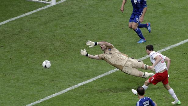 Ein Fußballspieler schießt auf das Tor, während der Torwart versucht, den Ball abzuwehren.