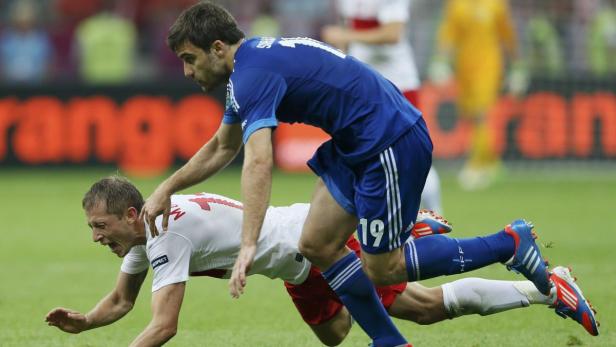 Ein Fußballspieler in Blau foult einen Spieler in Weiß während eines Spiels.