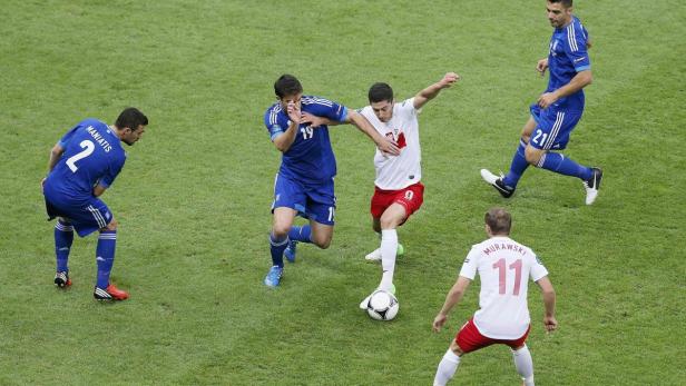 Robert Lewandowski im Zweikampf mit einem griechischen Gegenspieler während eines Fußballspiels.