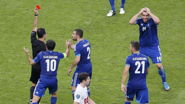 Ein Schiedsrichter zeigt einem griechischen Fußballspieler die Rote Karte.