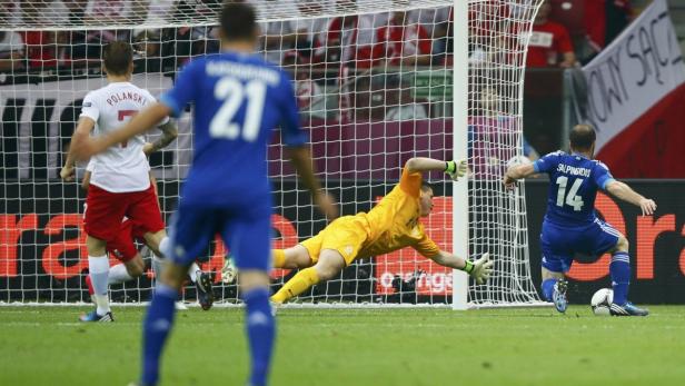 Ein Fußballspieler schießt auf das Tor, während der Torwart versucht, den Ball abzuwehren.