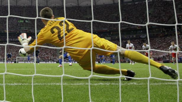 Ein Torwart hechtet, um einen Ball während eines Fußballspiels zu halten.