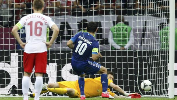 Ein Fußballspieler (Karagounis) schießt ein Tor, während ein Torwart auf dem Boden liegt.