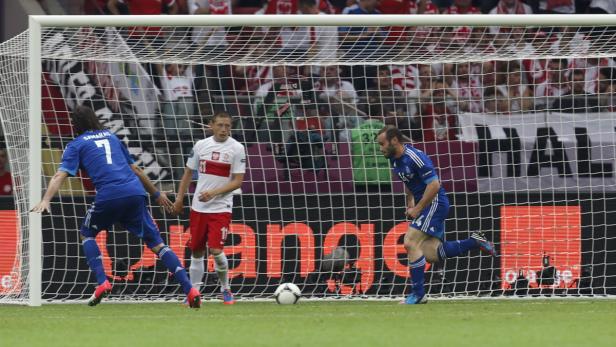 Ein Fußballspieler schießt ein Tor, während ein anderer Spieler zusieht.