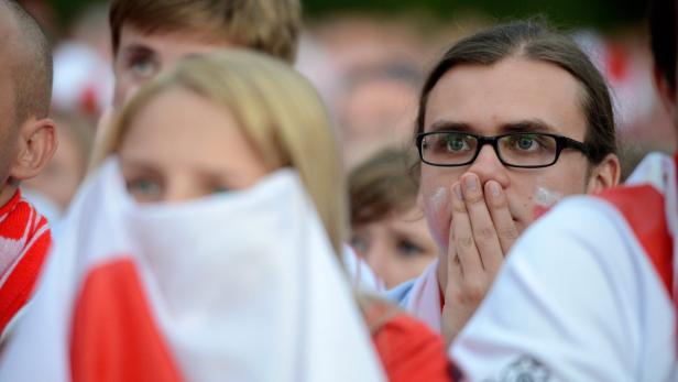 Besorgte Fußballfans mit polnischen Farben im Gesicht und einer Polen-Flagge.