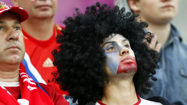 Ein Fan mit Gesichtsbemalung und Afro-Perücke schaut aufmerksam zu.