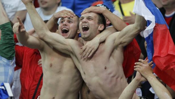 Zwei Männer jubeln mit nacktem Oberkörper und russischer Flagge im Publikum.