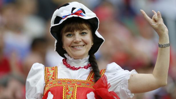 Eine lächelnde Frau in traditioneller russischer Tracht jubelt.
