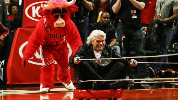 Richard Branson fährt auf einem roten Rollbrett, neben ihm das Maskottchen der Chicago Bulls.