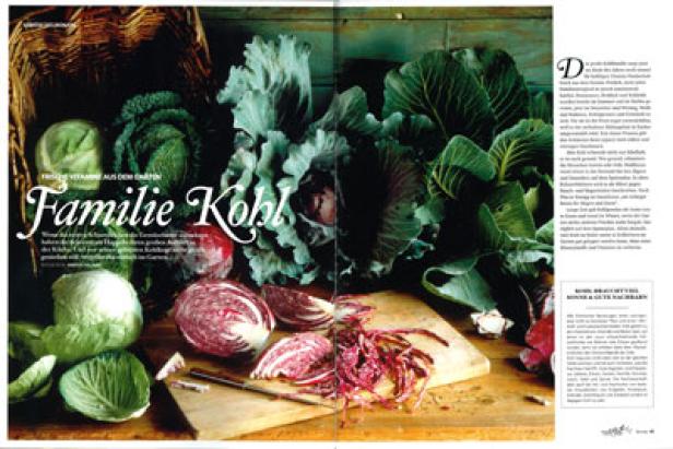 Verschiedene Kohlsorten liegen auf einem Holztisch, darunter Rotkohl und Weißkohl.