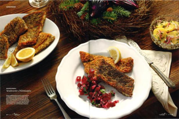 Gebratene Fischfilets werden mit Zitronen und Salat serviert.