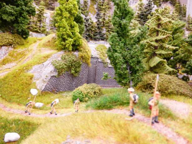 Eine Gruppe Wanderer auf einem Pfad in einer Miniaturlandschaft.