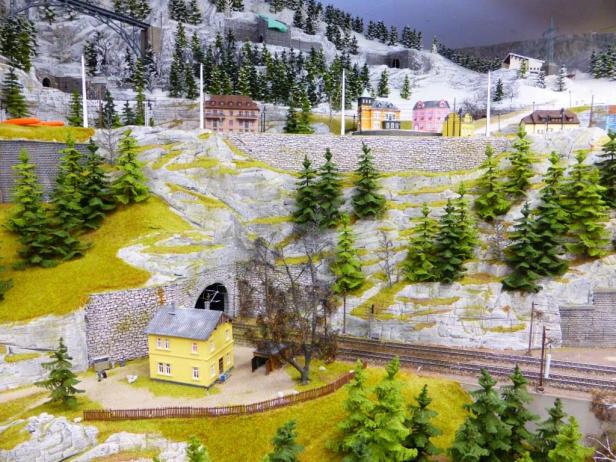 Eine Miniaturlandschaft mit Häusern, Bäumen und einer Eisenbahnstrecke.