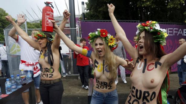 Drei barbusige Frauen mit Blumenkränzen protestieren mit aufgemalten Parolen gegen die EURO 2012.