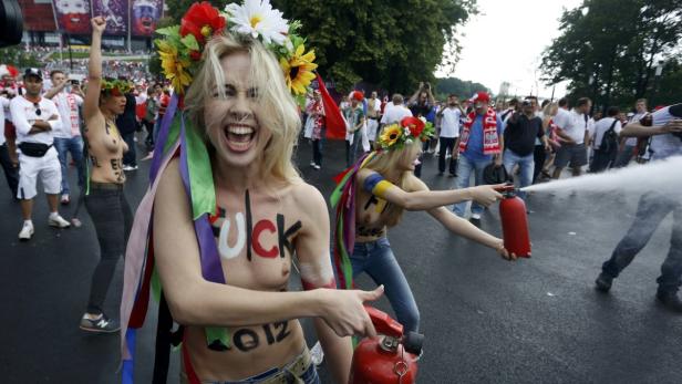 Frauen protestieren während der Fußball-Europameisterschaft 2012 mit aufgemalten Slogans und Feuerlöschern.