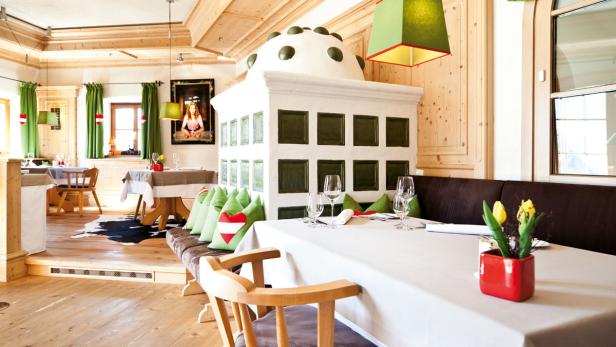 Ein traditionell eingerichtetes Restaurant mit Holzboden und einem Kachelofen.