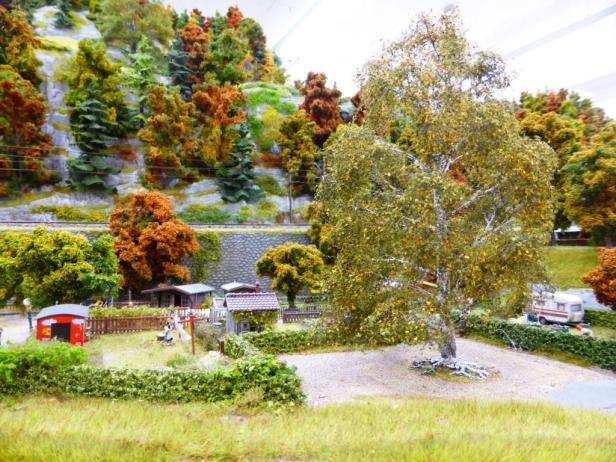 Eine Miniaturlandschaft mit Häusern, Bäumen und einem Wohnwagen.