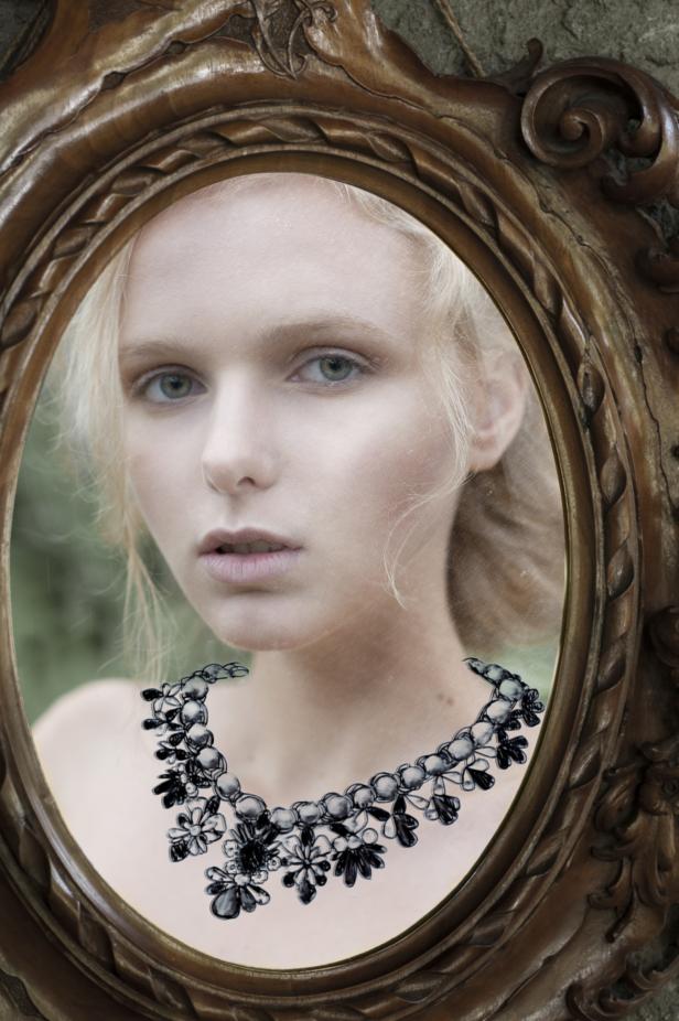 Eine junge Frau mit Halskette blickt in einen verzierten Spiegel.