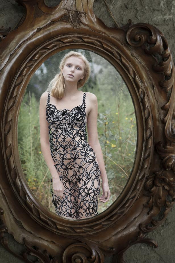 Eine junge Frau mit blonden Haaren, gesehen in einem verzierten Spiegel.