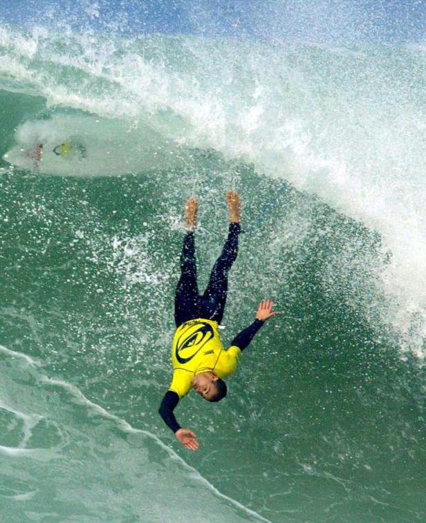 Ein Surfer stürzt kopfüber von einer Welle.